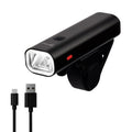 A black BRVIGA bicycle headlight with a USB charging cable shown below it on a plain white background. The headlight has a clear front lens, a small red indicator light, and the brand logo 'BRVIGA' is visible in the top left corner.